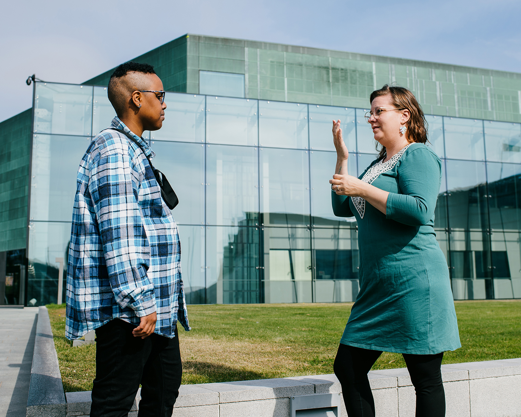 Kaksi ihmistä keskustelemassa viittomakielellä ulkona.